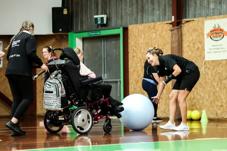 Coach supporting a young person using a wheelchair during an Abilities Unleashed event.