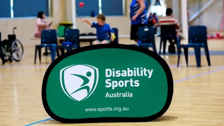 Disability Sports Australia sign reading “Disability Sports Australia” on indoor court with participants in background